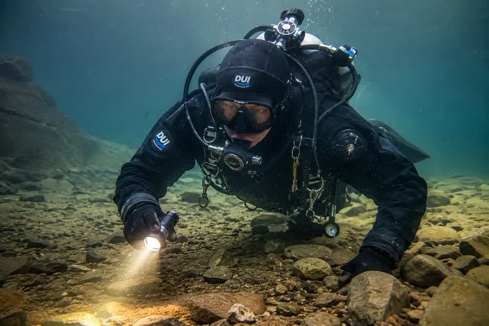 Diver searching the lake bed with a lamp