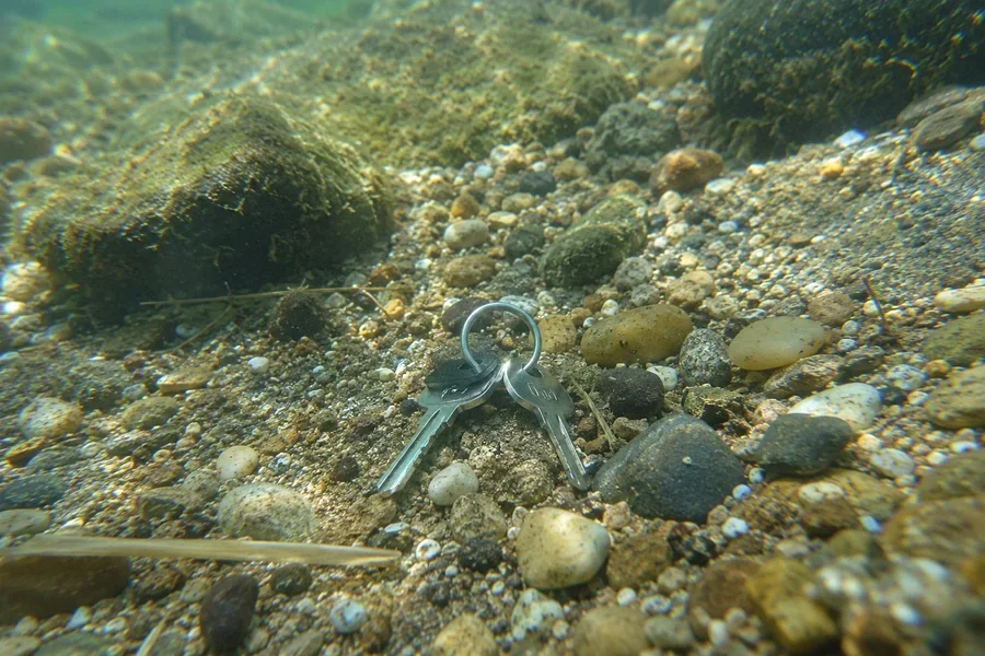 Verlorene Schlüssel auf Kiesboden unter Wasser